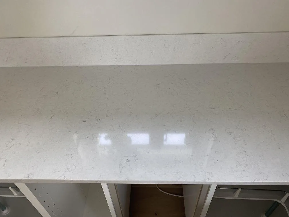Rak bänkyta i polerad Silestone Snowy Ibiza kvartskomposit med ljusreflexer och stänkskydd i köket i Tingsryd.
