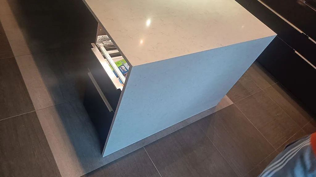 Sidovy av köksö i polerad Silestone Snowy Ibiza, kvartskomposit, med neddragen stensida och ljus ådring i Tomelilla.
