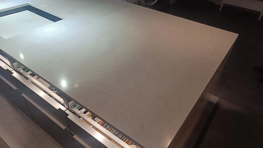 Ljus köksbänkskiva i polerad Silestone Snowy Ibiza med stor arbetsyta och förberett urtag på köksön i Tomelilla.