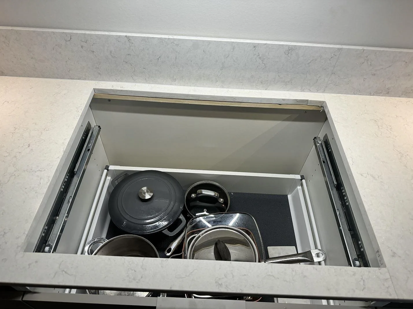 Detalj av bänkskivans öppna lådparti och polerad Silestone Snowy Ibiza runt arbetsytan i köket i Torslanda.