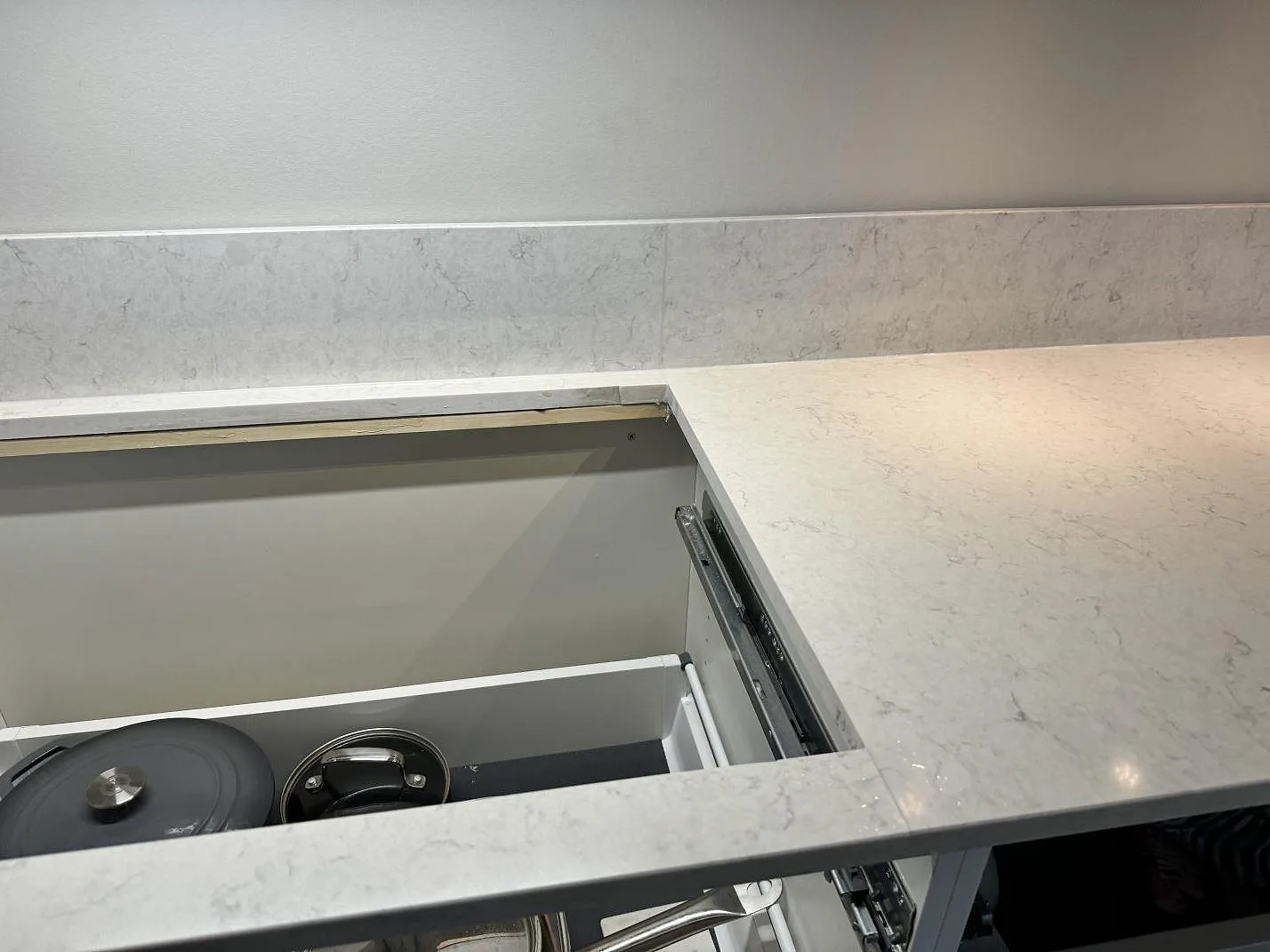 Närbild av polerad Silestone Snowy Ibiza runt lådöppningen med matchande stänkskydd i köket i Torslanda.