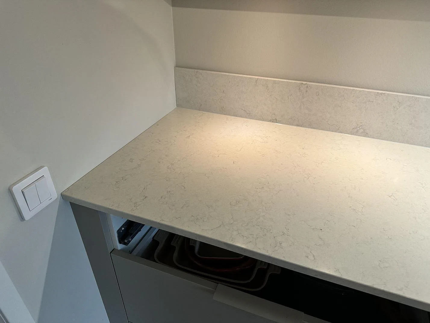 Hörndel av köksbänkskiva i polerad Silestone Snowy Ibiza med 12 mm stänkskydd och ljus ådring i Torslanda.
