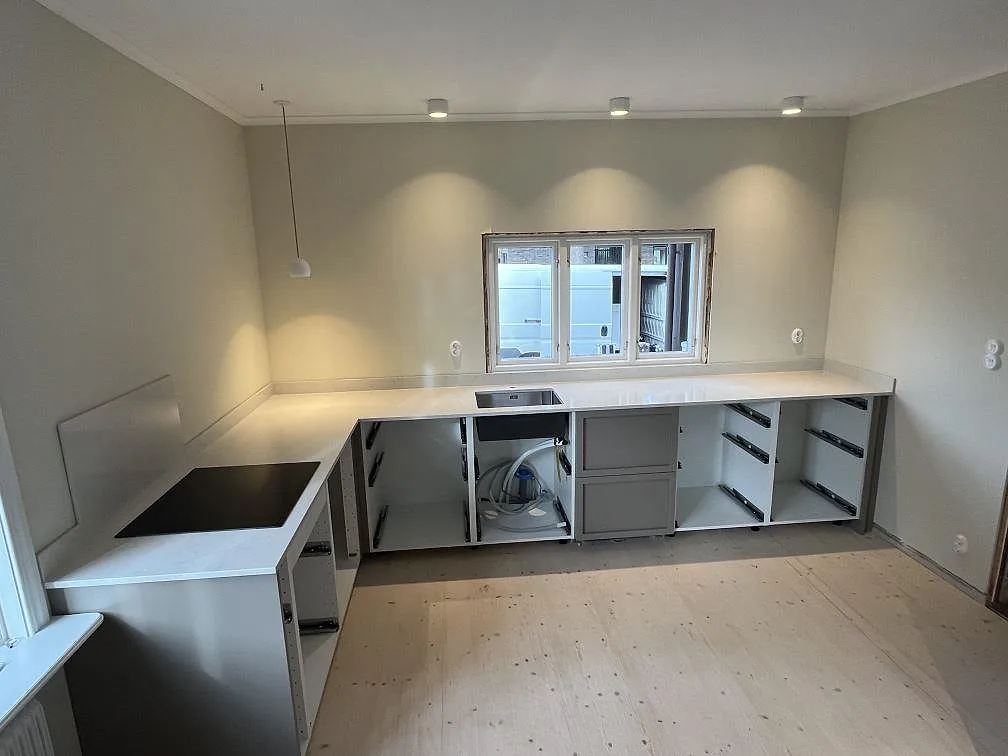 Polerad köksbänkskiva i Silestone Snowy Ibiza längs fönsterväggen med underlimmad rostfri diskho i Tranås.