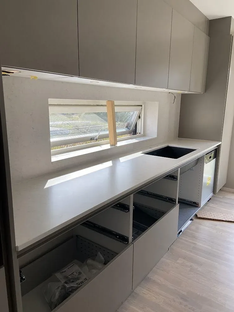 Installerad bänkskiva i vit Silestone Snowy Ibiza kvartskomposit längs en köksvägg i Trelleborg, fotad under montering.