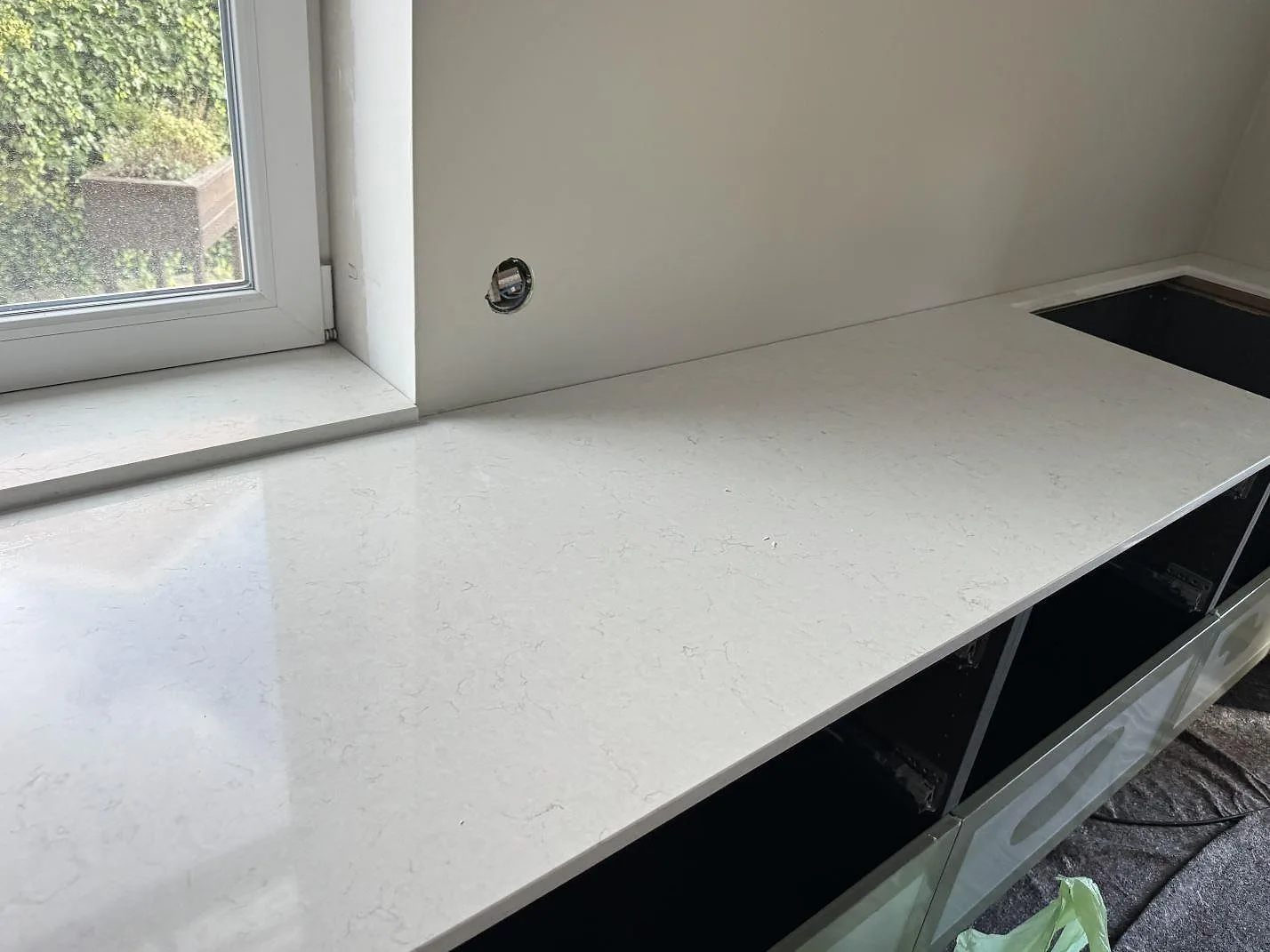 Lång köksbänk i polerad kvartskomposit Silestone Snowy Ibiza med hällöppning och ljus ådring i Trelleborg.