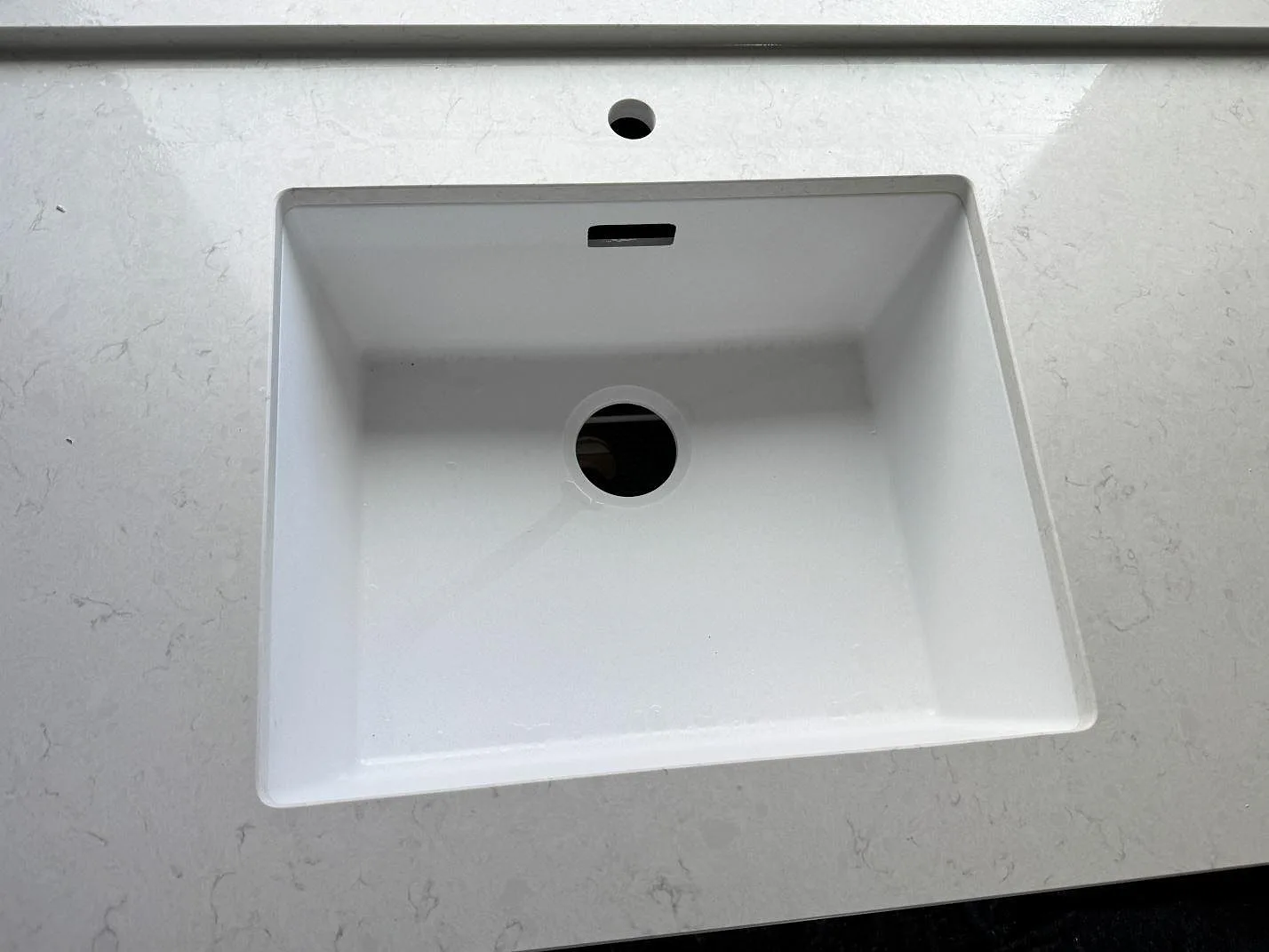 Närbild på vit diskho i polerad kvartskomposit Silestone Snowy Ibiza med synlig grå ådring i köket i Trelleborg.