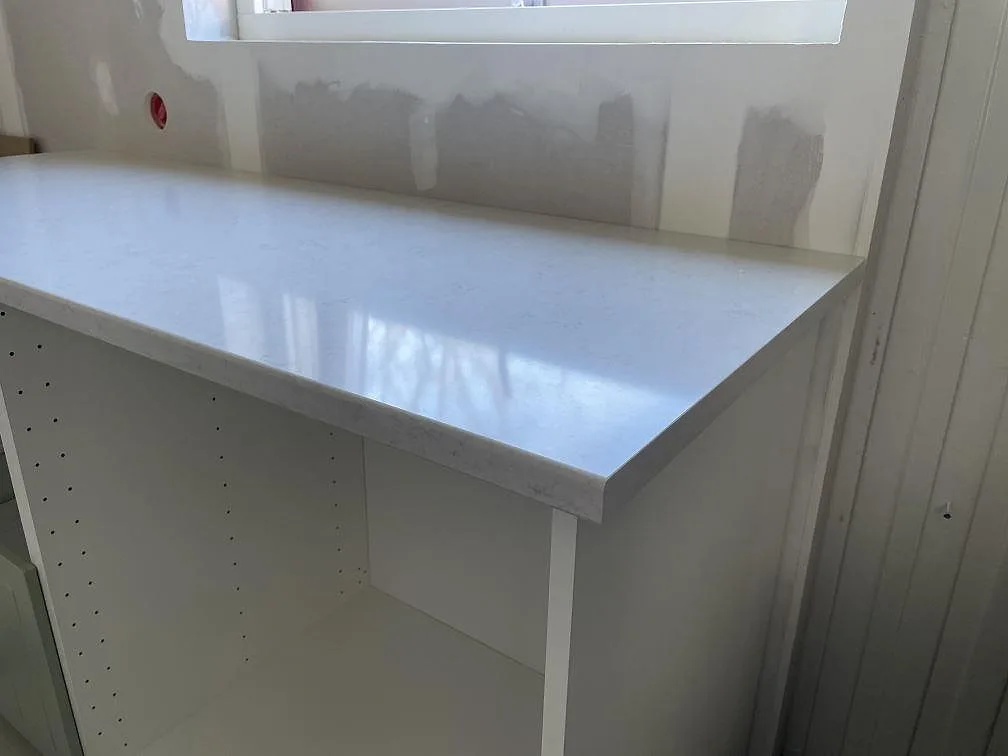 Köksbänkskiva i blank Silestone Snowy Ibiza med mjukt rundad kant under fönstret i ett kök i Trollhättan.