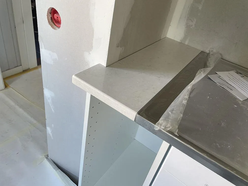 Köksbänkskiva i Silestone Snowy Ibiza som möter en fristående rostfri spis i ett kök i Trollhättan.