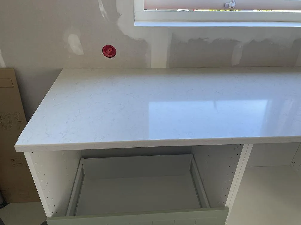 Polerad vit Silestone Snowy Ibiza med fin grå ådring på halvön i ett kök under montering i Trollhättan.