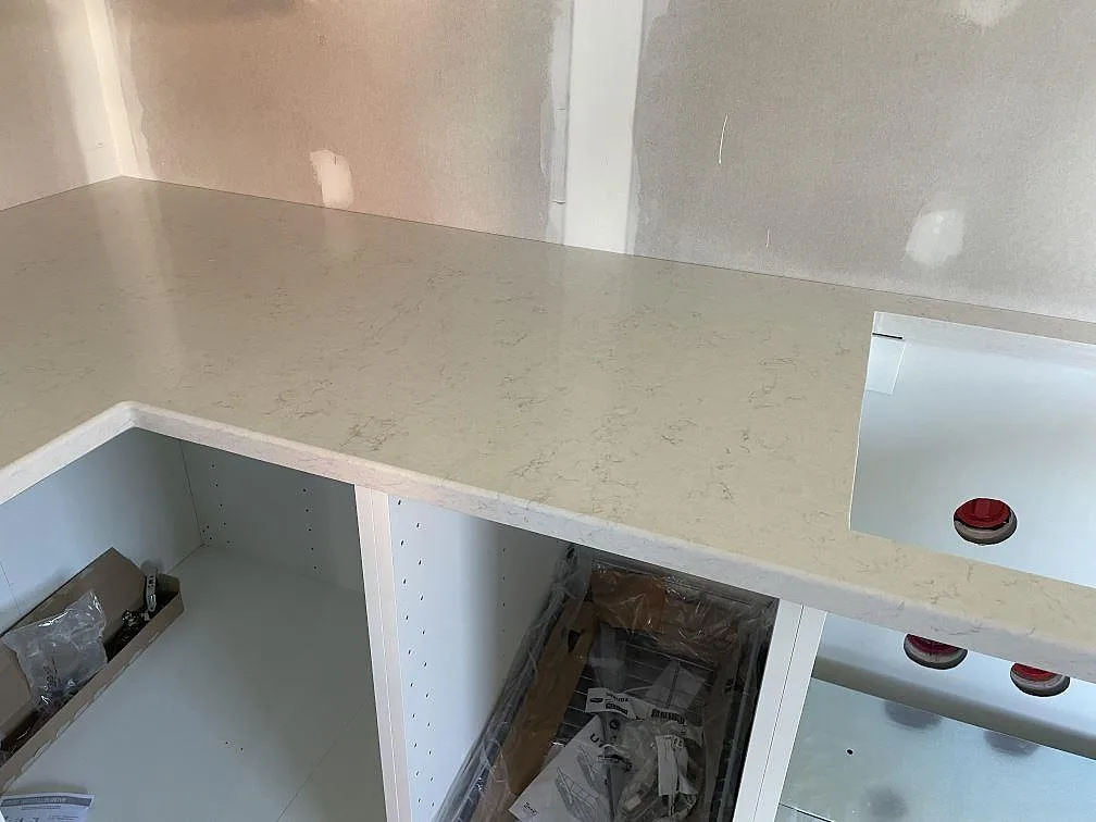 L-formad köksbänkskiva i vit Silestone Snowy Ibiza med urtag och synlig grå ådring i ett kök i Trollhättan.