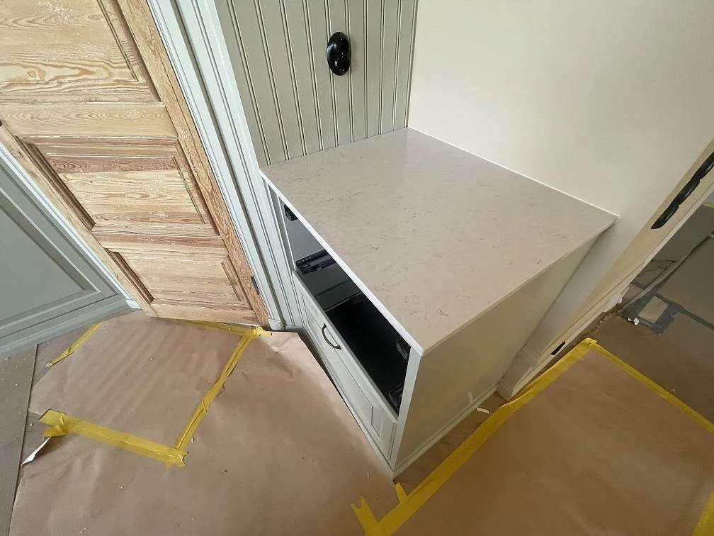 Mindre sidobänk i polerad Silestone Snowy Ibiza vid panelvägg, monterad som arbetsyta i köket i Trosa.