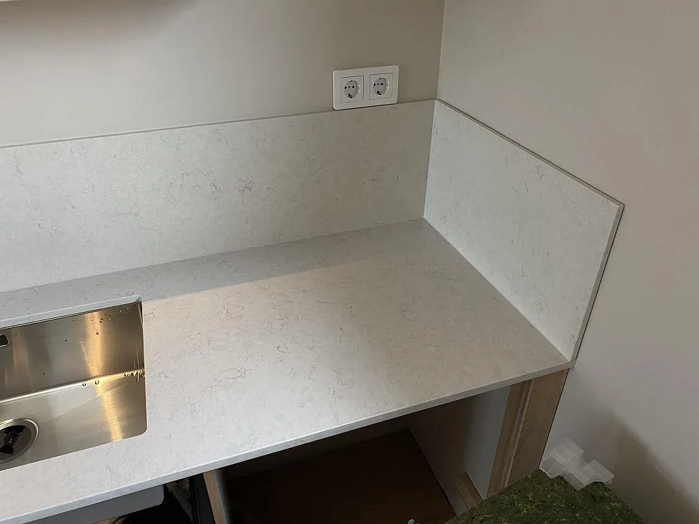 Diskhohörn i polerad Silestone Snowy Ibiza med rostfri diskho, vägguttag och stänkskydd i Tygelsjö.