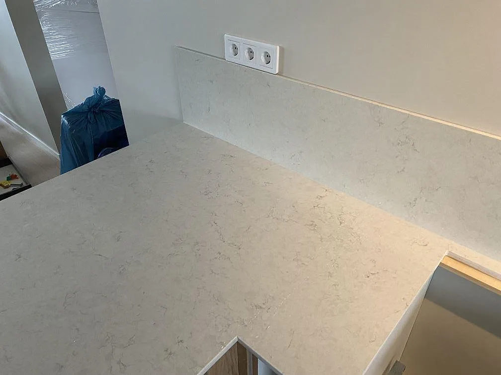 Närbild på polerad Silestone Snowy Ibiza där ljus ådring möter ett lågt stänkskydd vid köksbänken i Tygelsjö.
