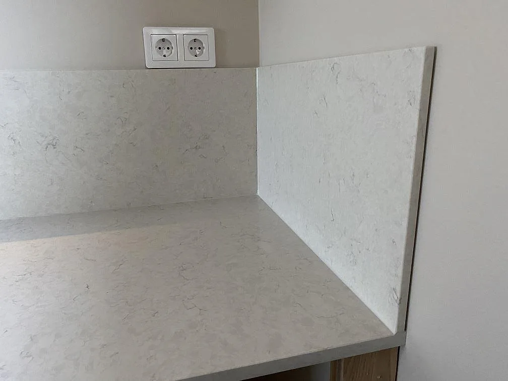 Änddetalj av köksbänkskiva och stänkskydd i polerad Silestone Snowy Ibiza i ett kök i Tygelsjö.