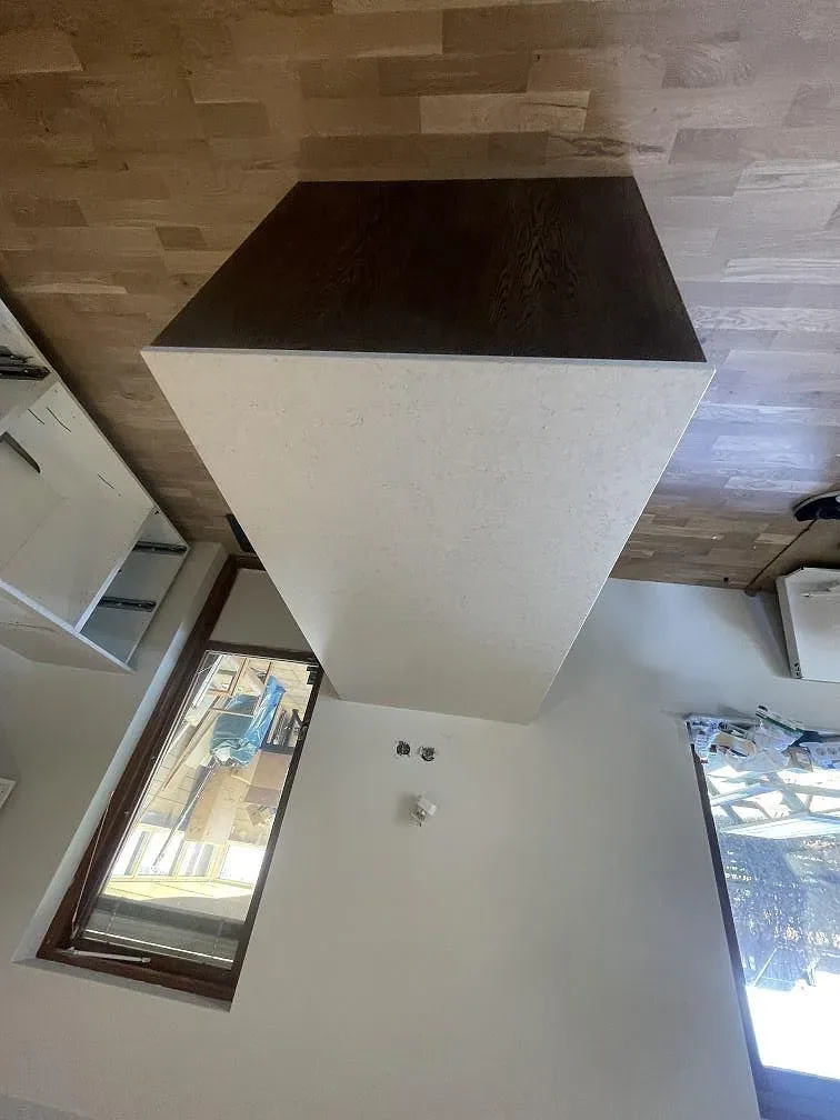 Vit Silestone Snowy Ibiza i matt utförande på köshalvön mot fönsterväggen, med synlig mörk träsockel och slät stenkant, i ett kök i Tygelsjö.