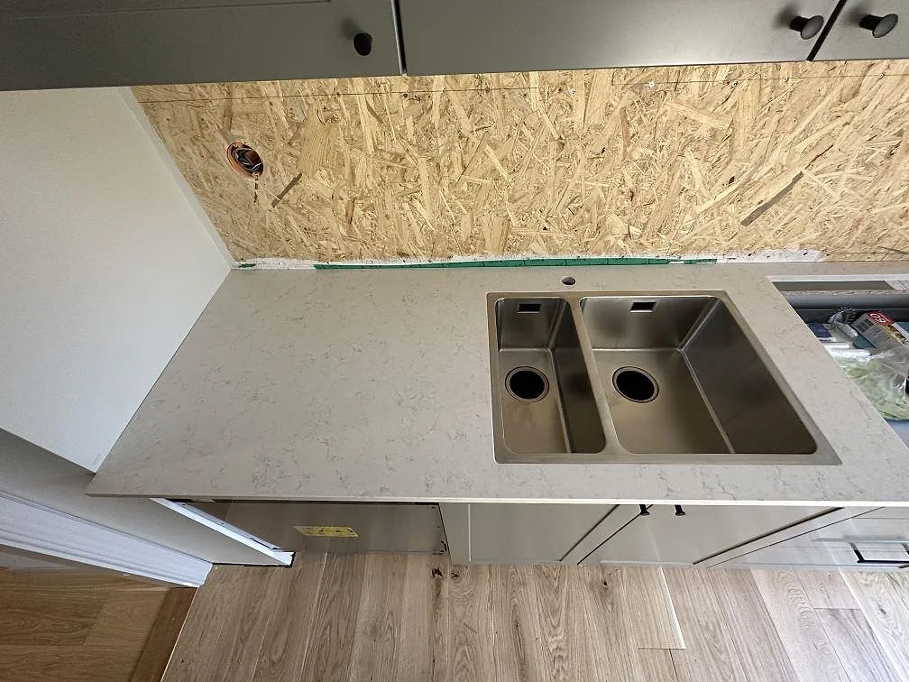 Närbild av polerad Silestone Snowy Ibiza som köksbänkskiva med underlimmad rostfri dubbelho i Uddevalla.
