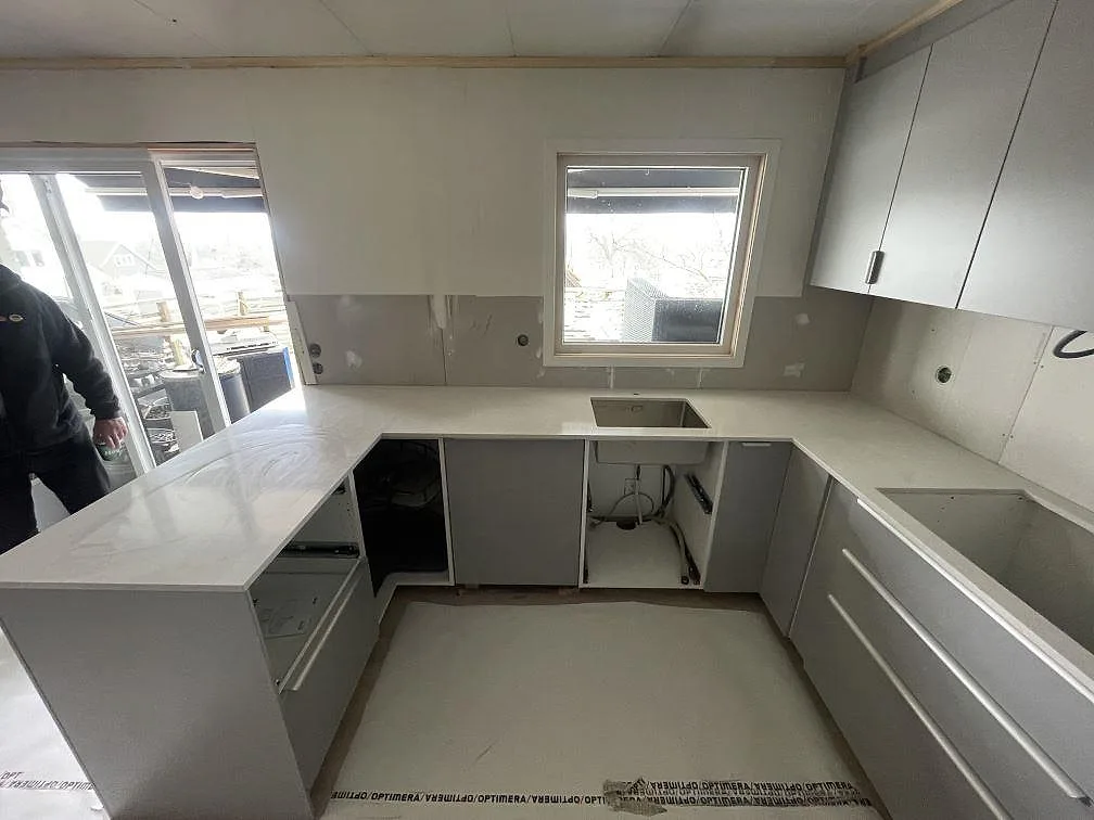 Köksö och bänkskiva i vit Silestone Snowy Ibiza i ett kök i Ulricehamn, fotograferad under montering med fönster och förberett diskhourtag.