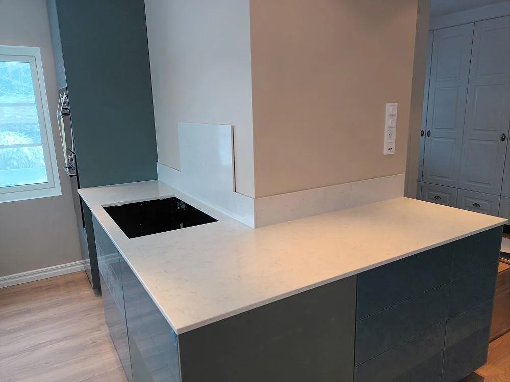 Närbild på köksö och bänkskiva i polerad Silestone Snowy Ibiza med hällzon och stänkkant i Upplands Väsby.