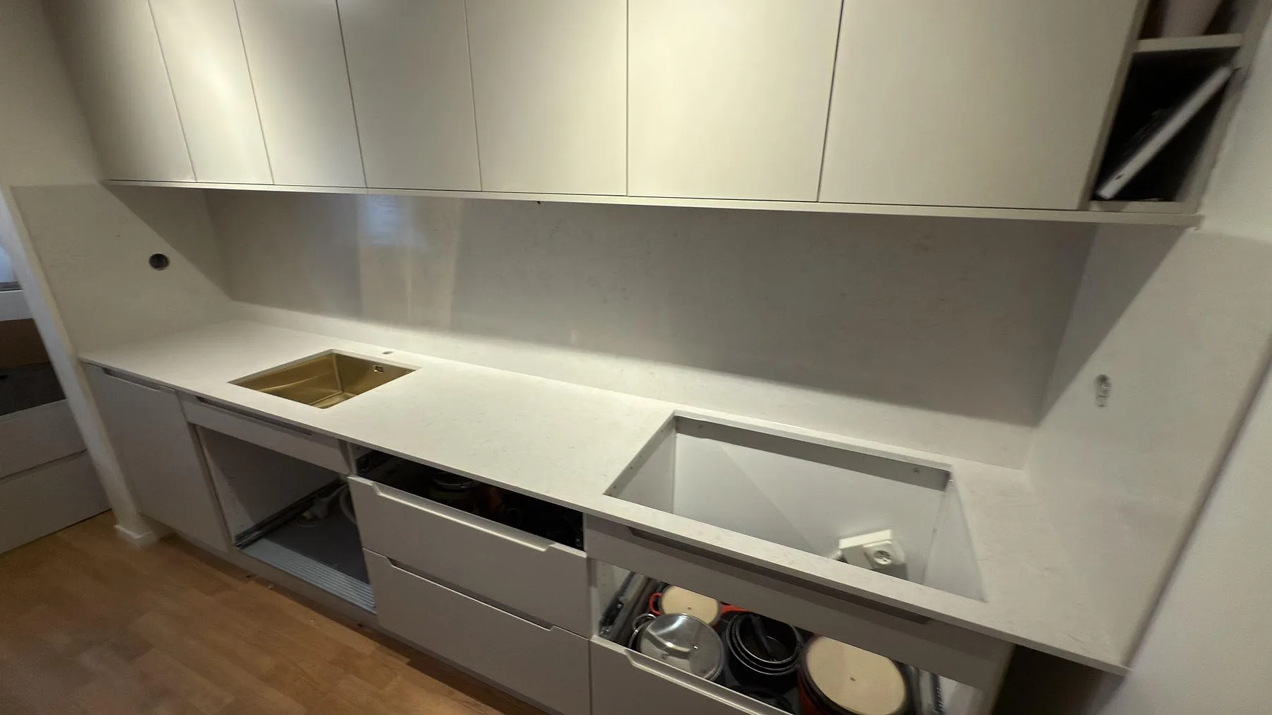 Översikt av polerad Silestone Snowy Ibiza bänkskiva med diskho, hällöppning och hög stänkskiva i kök i Upplands Väsby.