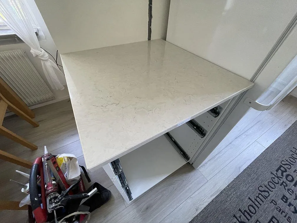 Separat bänkdel i polerad Silestone Snowy Ibiza, ljus kompositsten med grå teckning, monterad på köksstommar i Upplands Väsby.