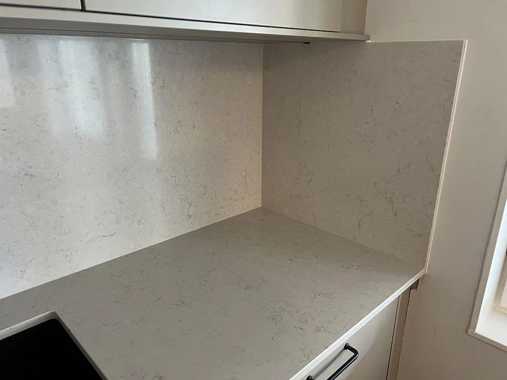 Närbild på polerad Silestone Snowy Ibiza som bänkskiva och stänkskydd vid hörn i kök i Värnamo.