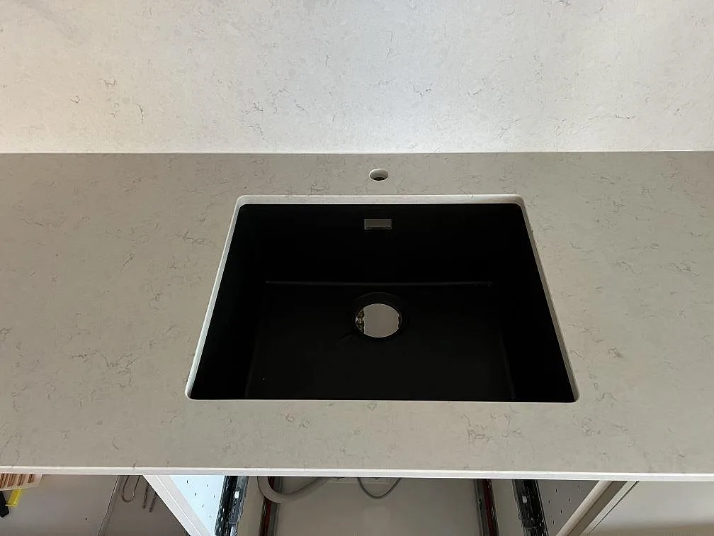 Svart underlimmad diskho monterad i polerad Silestone Snowy Ibiza med ljus komposityta i Värnamo.