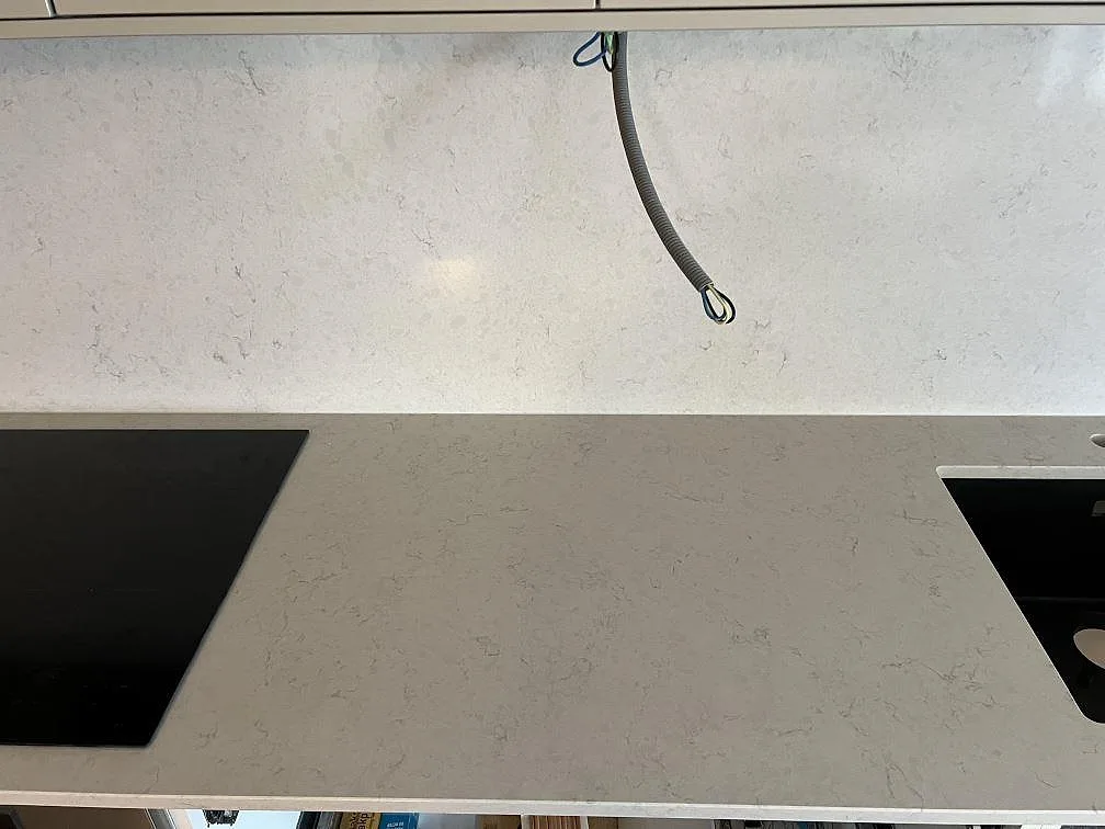 Polerad Silestone Snowy Ibiza mellan svart häll och svart diskho med matchande stänkskydd i Värnamo.