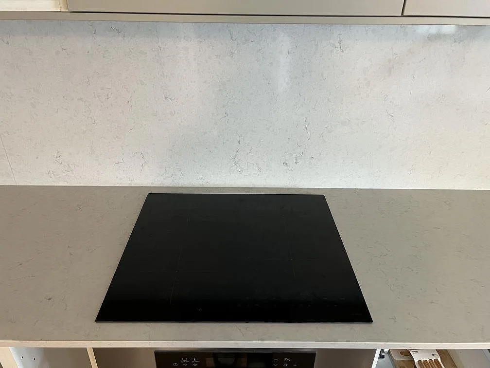 Svart häll i köksbänkskiva av polerad Silestone Snowy Ibiza med ljust stänkskydd i Värnamo.