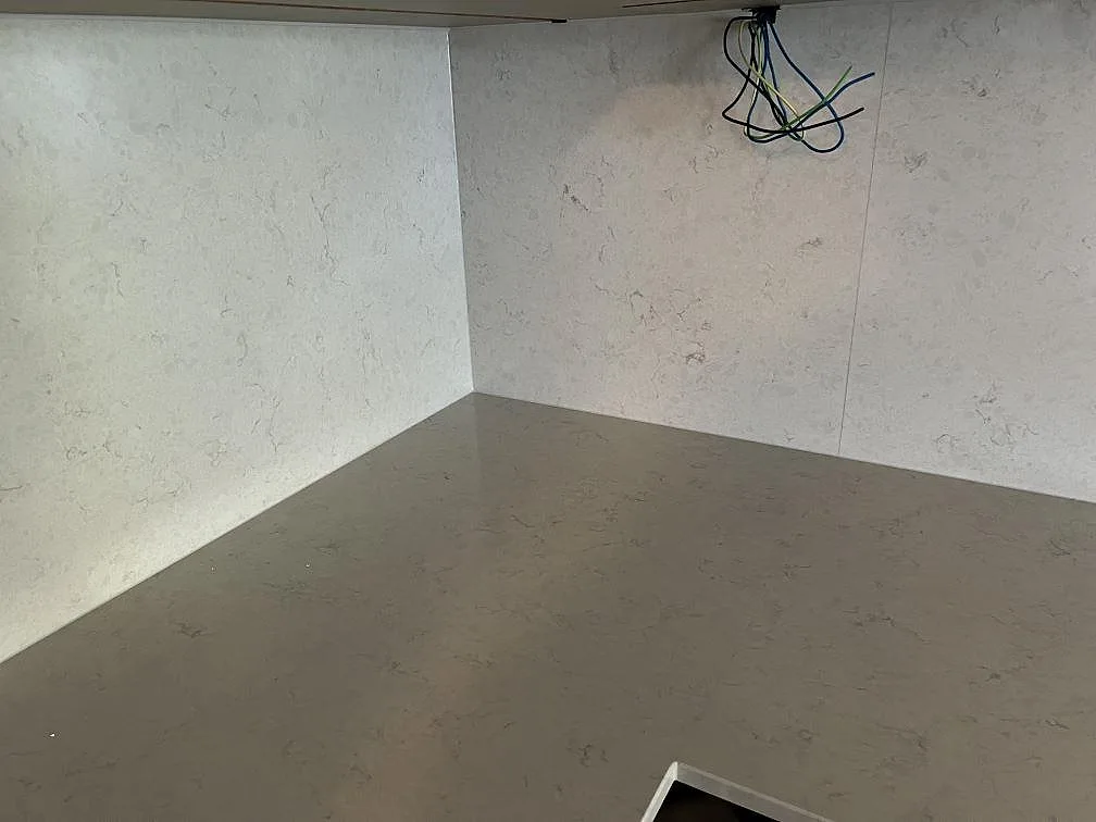 Hörnparti med polerad Silestone Snowy Ibiza som bänkskiva och högt stänkskydd under montering i Värnamo.