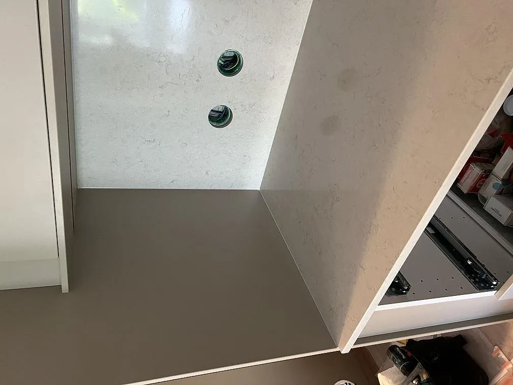 Detalj av polerad Silestone Snowy Ibiza vid köksbänk och stänkskydd med eluttag under montering i Värnamo.