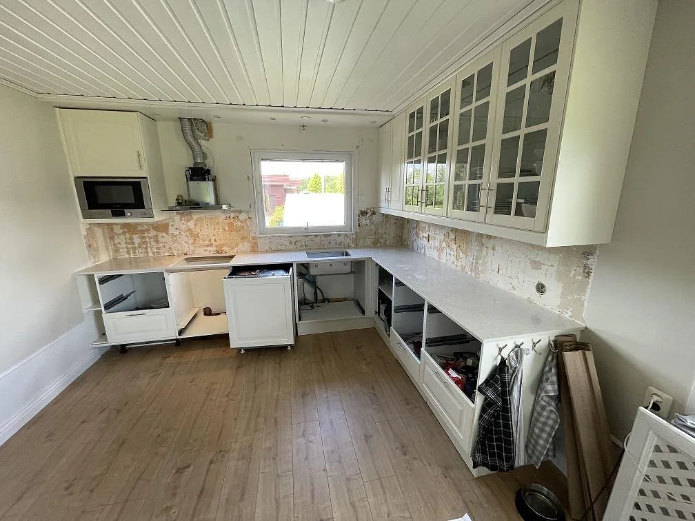 L-formad köksbänkskiva i polerad Silestone Snowy Ibiza kvartskomposit med diskzon och hällöppning i ett kök under montering i Västerås.