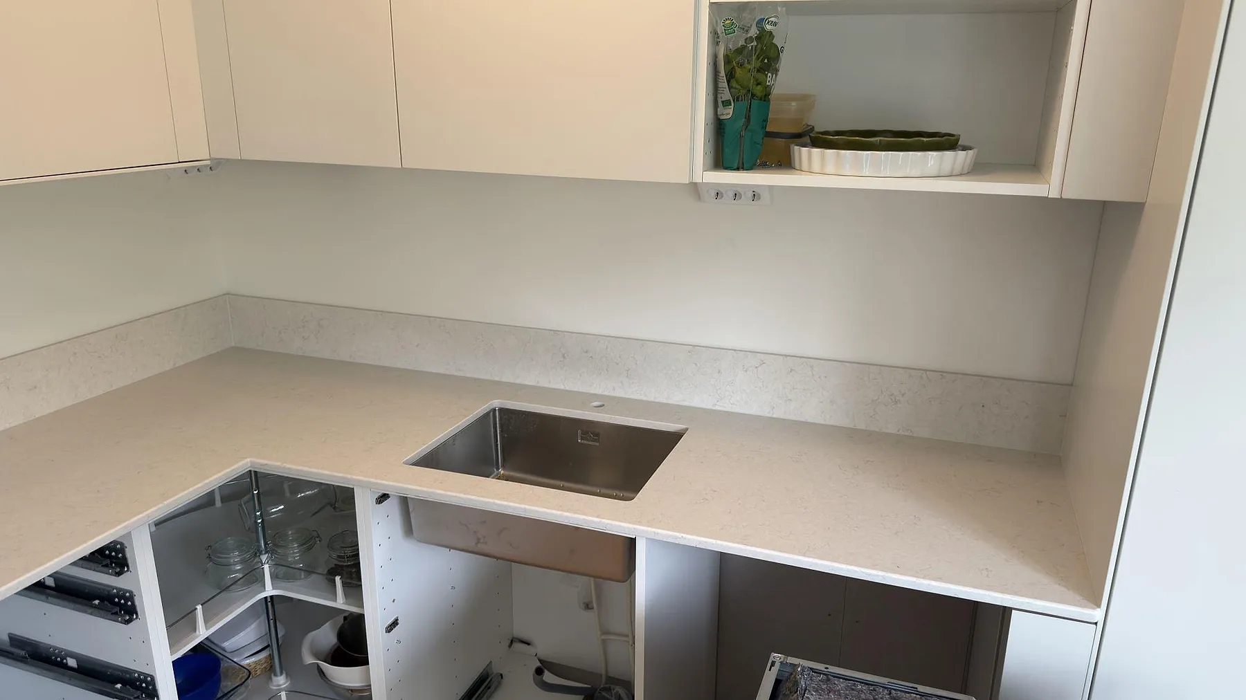 Köksbänkskiva i polerad Silestone Snowy Ibiza kvartskomposit med rostfri diskho och matchande stänkskydd i ett kök i Västerås.
