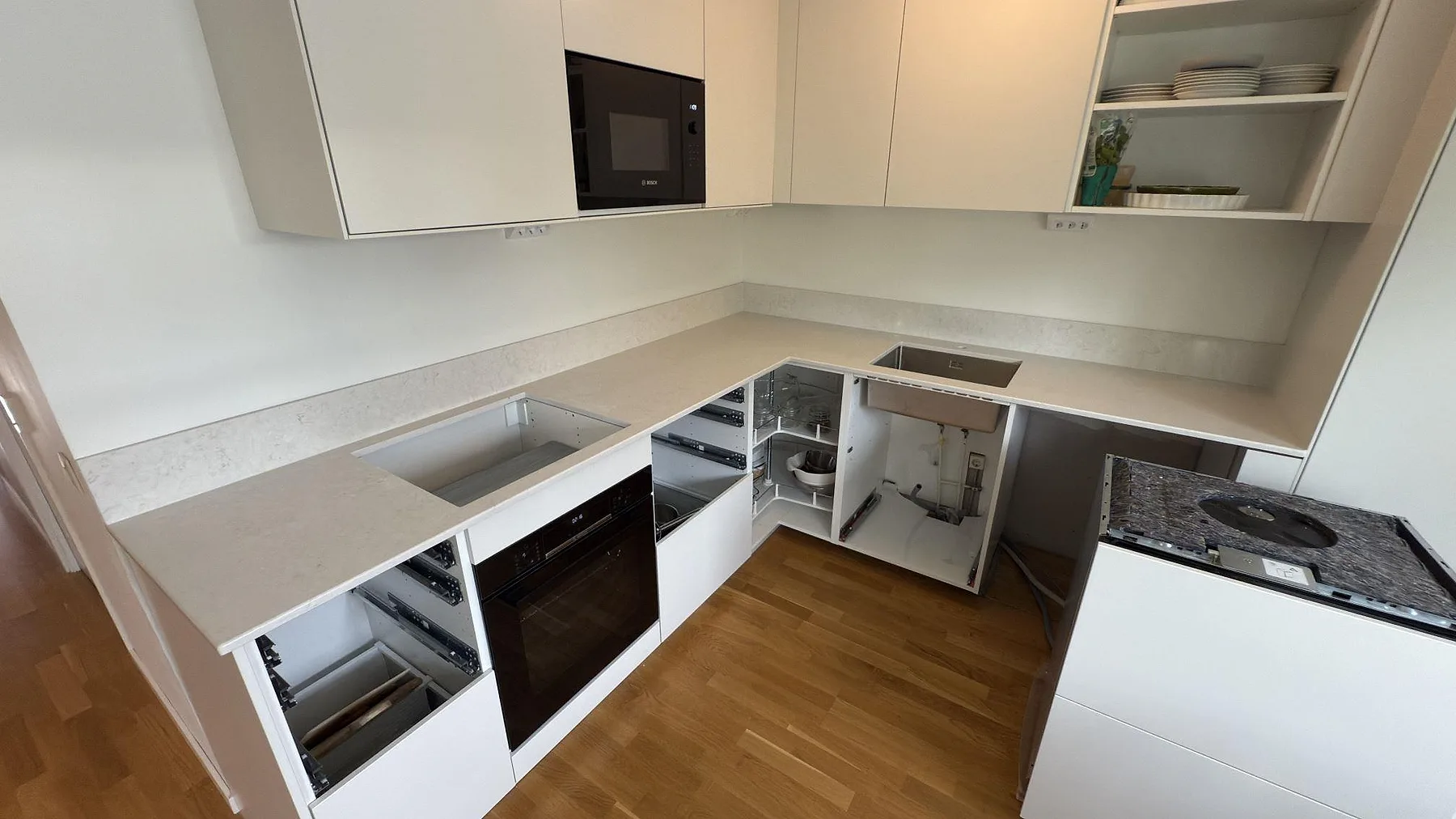 L-formad köksbänkskiva i polerad Silestone Snowy Ibiza kvartskomposit med stänkskydd, rostfri diskho och hällöppning i Västerås.