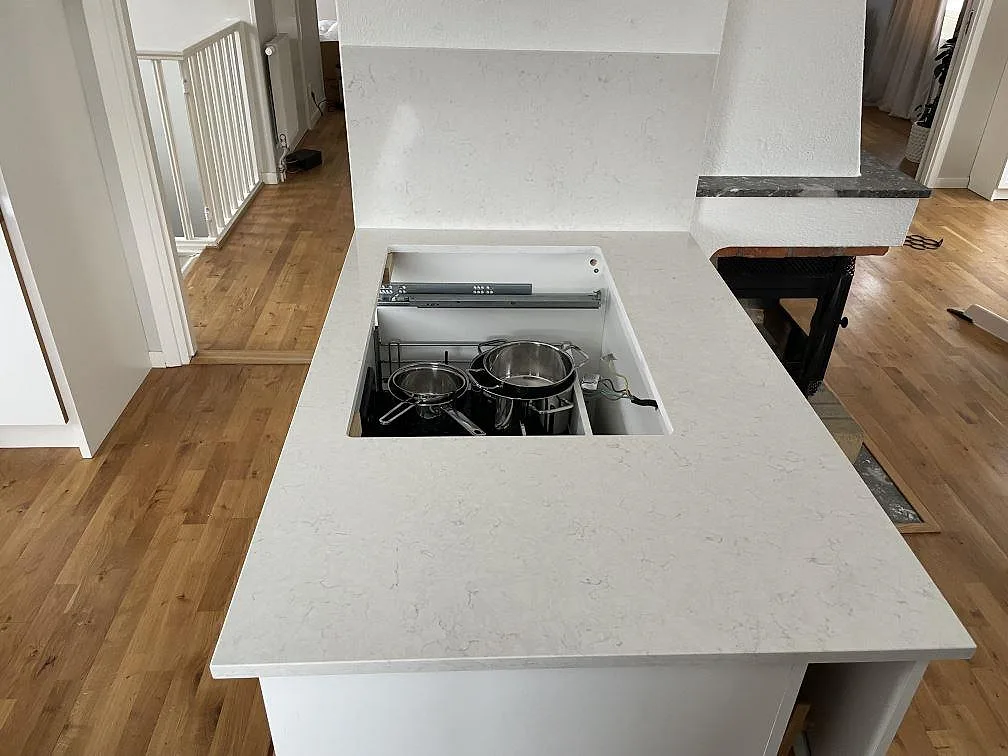 Fristående köksö i vit Silestone Snowy Ibiza, polerad, med urtag för häll i ett kök i Västerås.