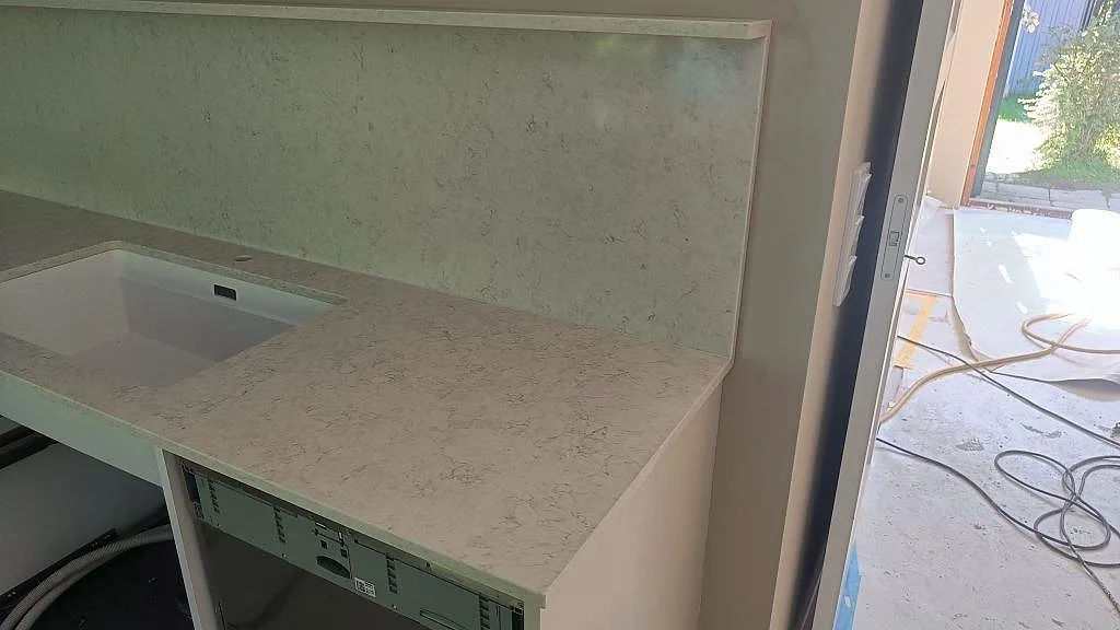 Detalj av polerad Silestone Snowy Ibiza som köksbänkskiva och stänkskydd bredvid stora glasdörrar i Västra Frölunda.