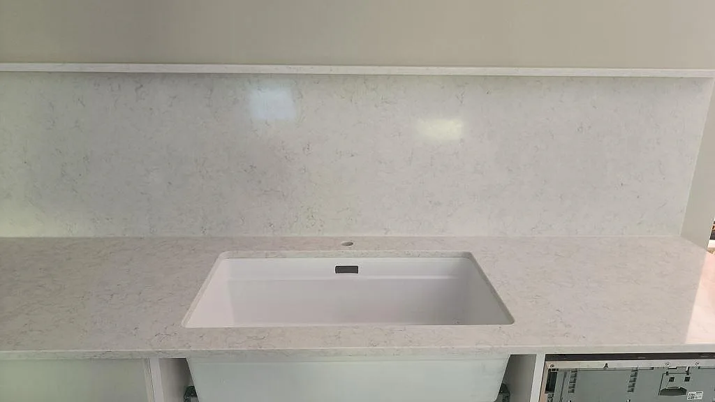 Närbild på vit underlimmad diskho i polerad Silestone Snowy Ibiza med matchande stänkskydd i ett kök i Västra Frölunda.