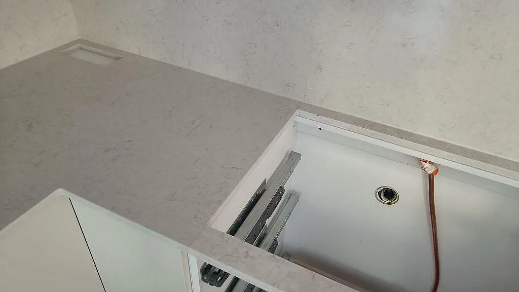 Arbetsyta i polerad Silestone Snowy Ibiza med hälluttag, ljus ådring och öppna vita stommar i Västra Frölunda.