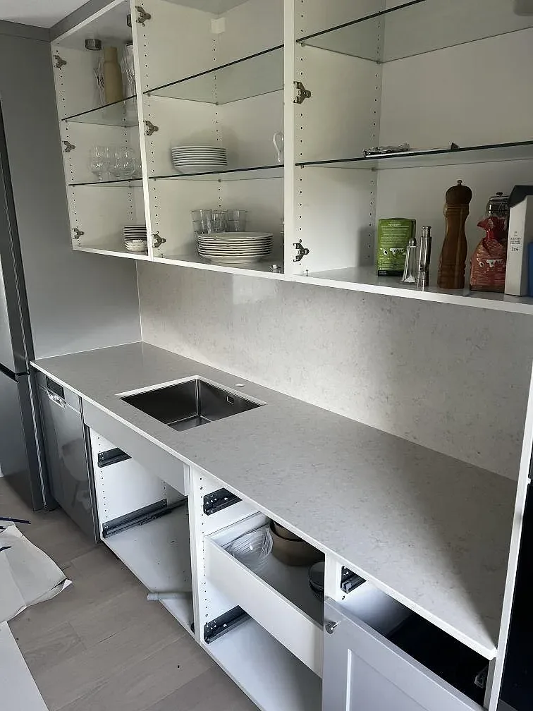 Polerad Silestone Snowy Ibiza bänkskiva i komposit med diskhozon och öppna vita köksstommar i Västra Frölunda.