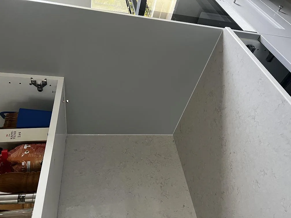 Hörnvy av polerad Silestone Snowy Ibiza komposit med 12 mm uppkant och ljus skåpsinredning under montering i Västra Frölunda.