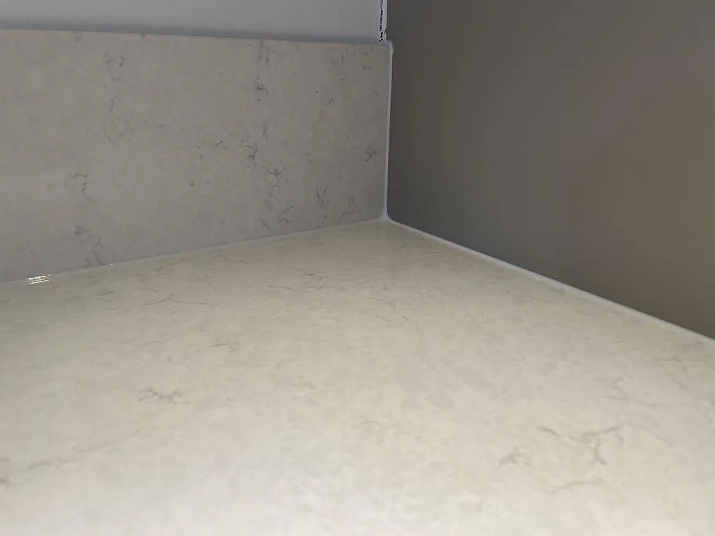 Detalj av polerad Silestone Snowy Ibiza med bänkskiva, stänkskydd och diskret grå ådring i köket i Västra Frölunda.