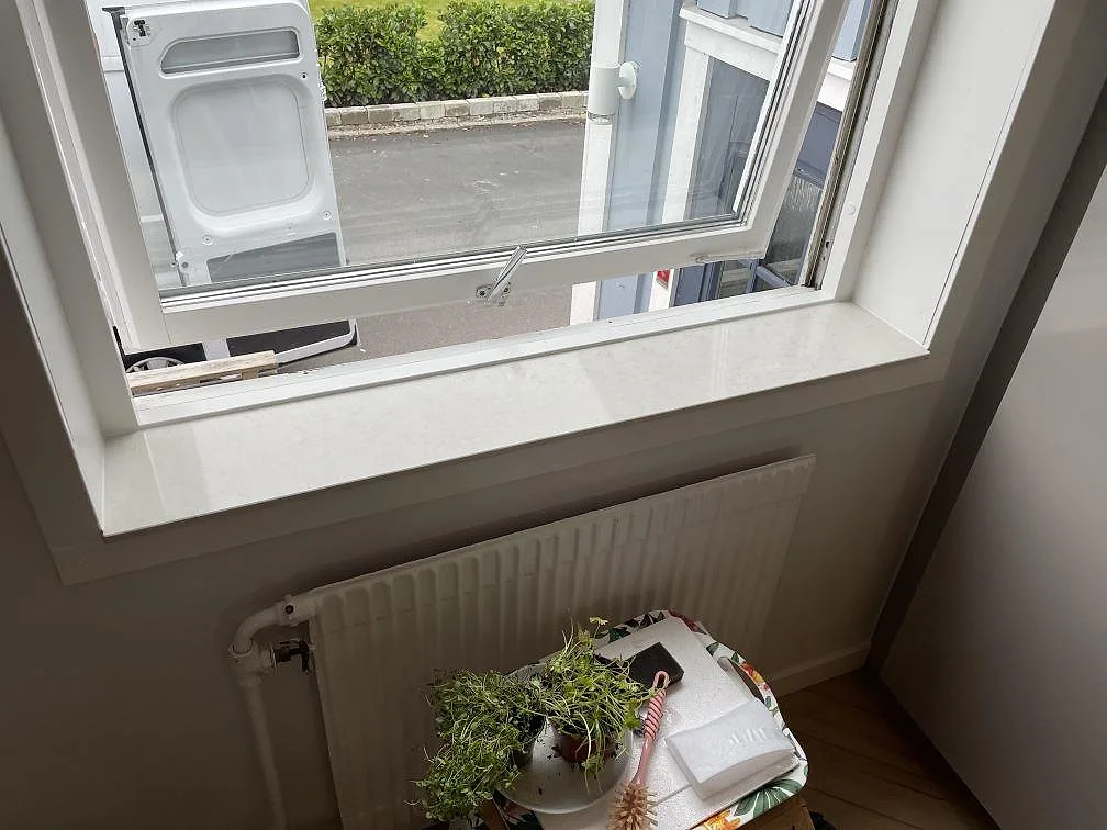 Ljus fönsterbänk i Silestone Snowy Ibiza, polerad, monterad över radiator i ett kök i Västra Frölunda.