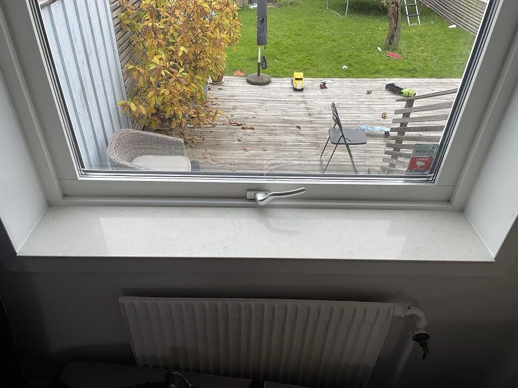 Fönsterbänk i vit Silestone Snowy Ibiza med polerad yta och mjuk grå ådring vid fönster i Västra Frölunda.