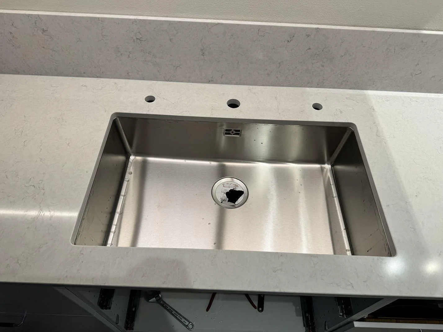 Närbild på underlimmad rostfri diskho i polerad Silestone Snowy Ibiza med förborrade hål för blandare i Västra Frölunda.