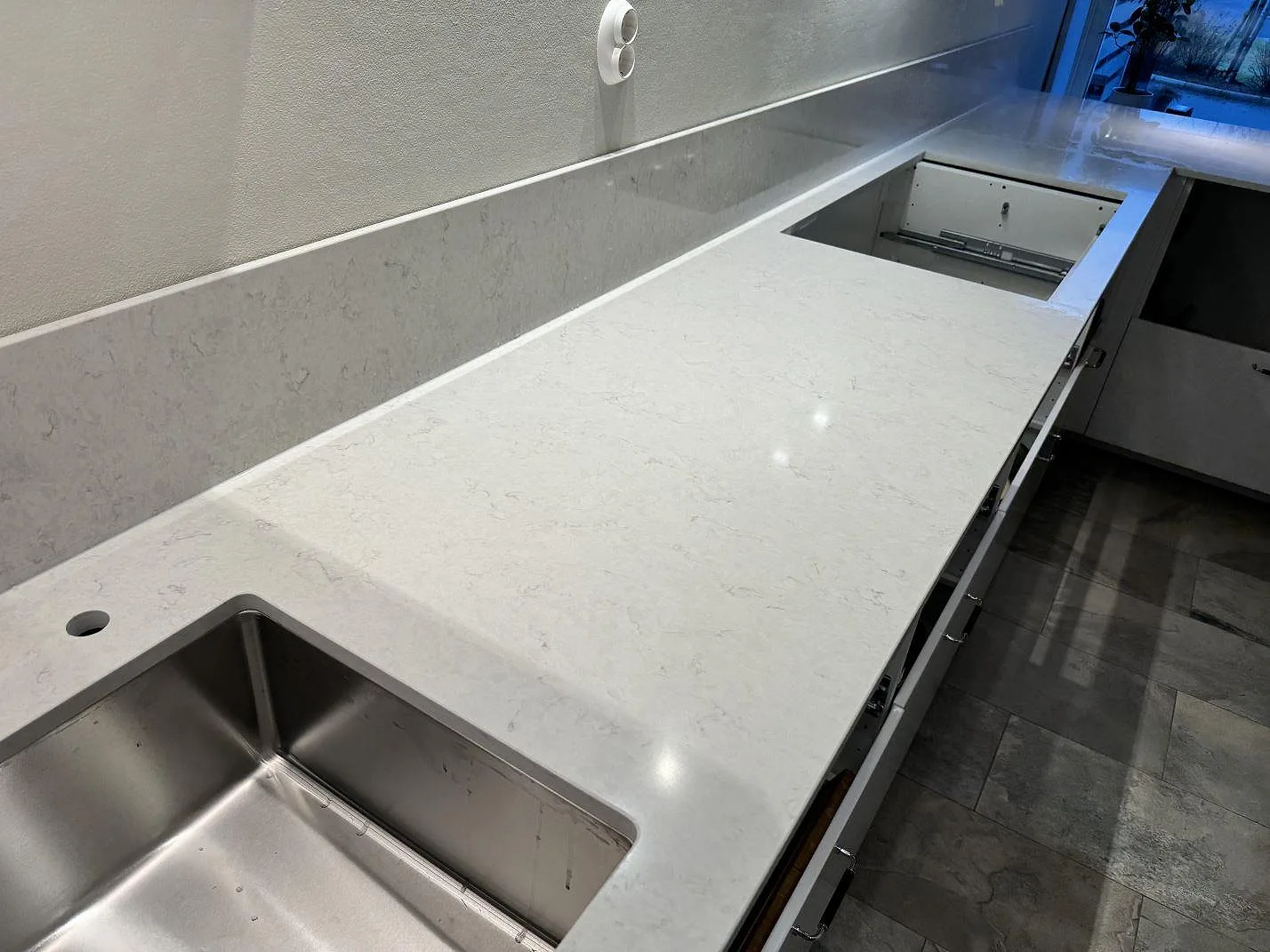 L-formad köksbänkskiva i polerad Silestone Snowy Ibiza med två underlimmade rostfria hoar och uppvikt stänkkant i Västra Frölunda.