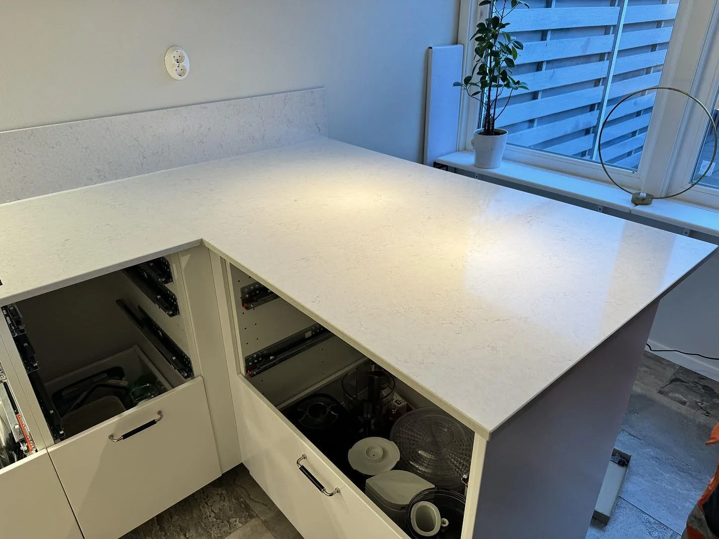 Stor ljus arbetsyta i polerad Silestone Snowy Ibiza över öppna kökslådor och vit stomme i Västra Frölunda.