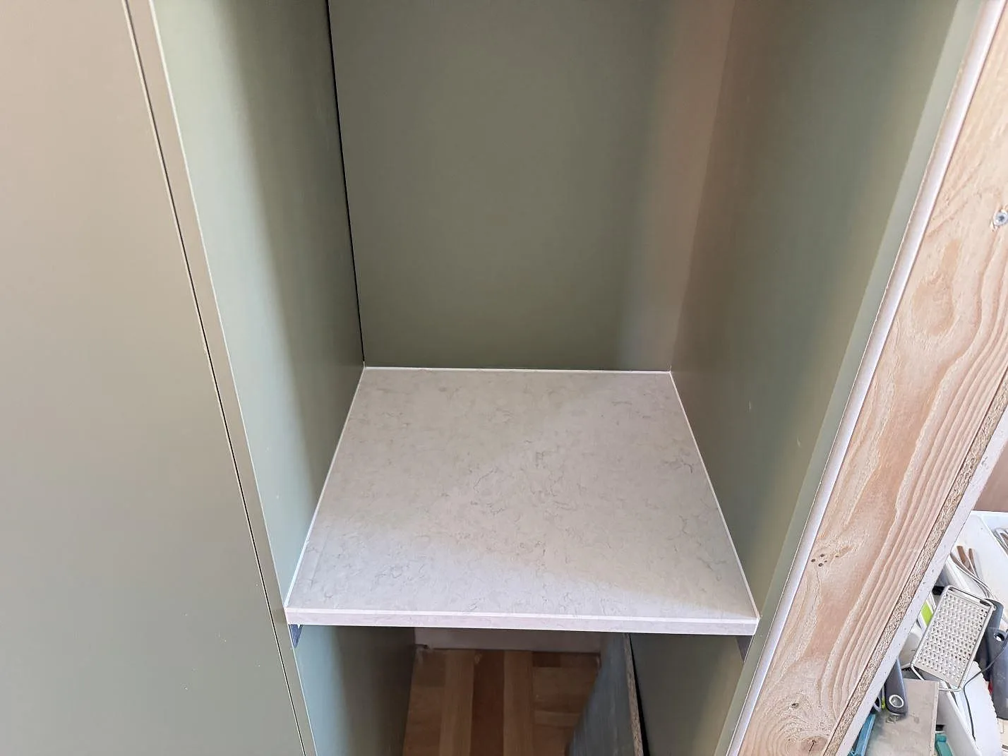 Mindre nischyta i polerad Silestone Snowy Ibiza kvartskomposit monterad mellan gröna skåpsidor i Västra Frölunda.