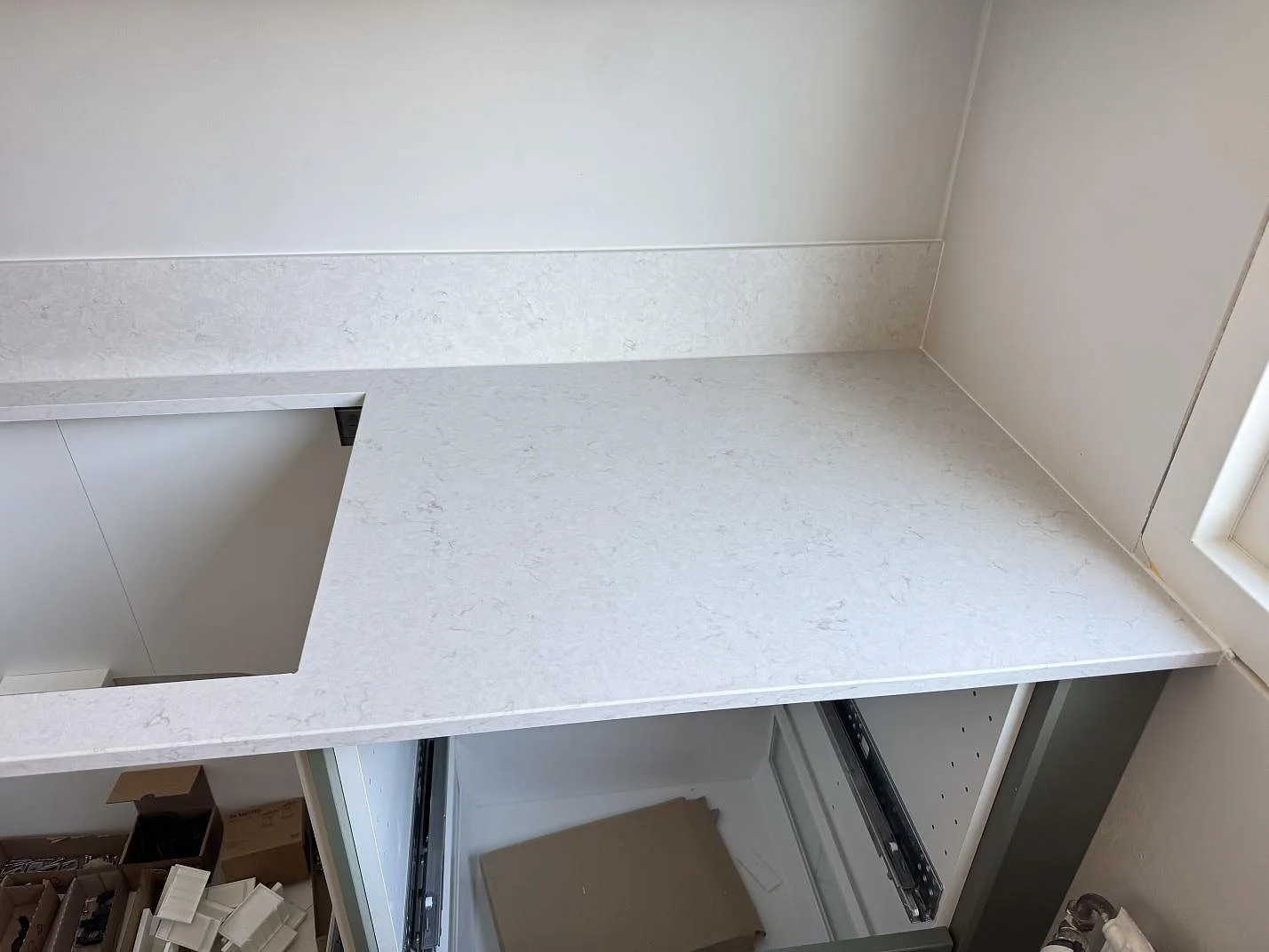 Polerad köksbänkskiva i Silestone Snowy Ibiza kvartskomposit med ljus grå ådring, stänkskydd och fönsterhörn i Västra Frölunda.