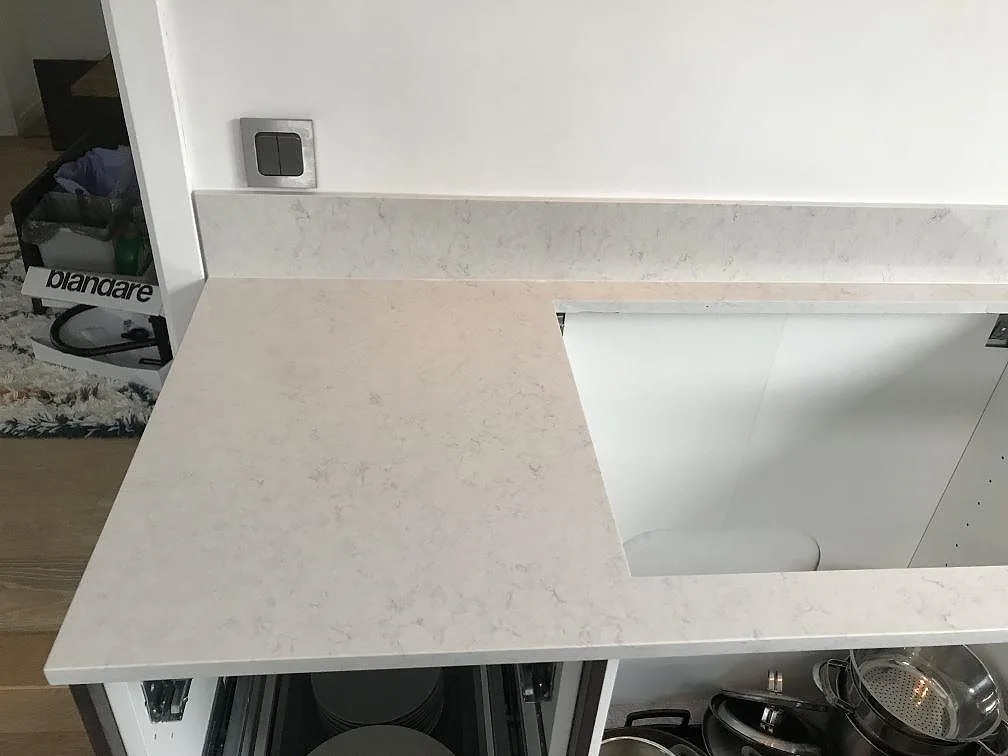 Underlimmad svart kompositdiskho i polerad Silestone Snowy Ibiza, vit kvartskomposit med fin ådring i ett kök i Växjö.