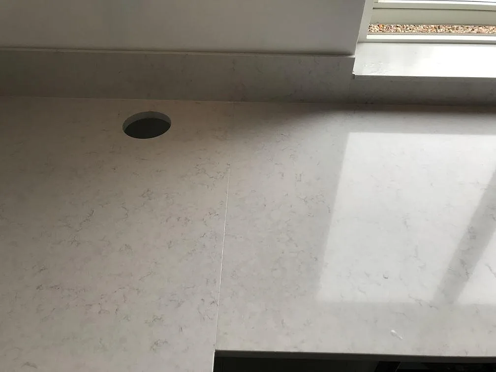 Matchande fönsterbänk i polerad Silestone Snowy Ibiza vid köksfönstret i ett kök i Växjö.