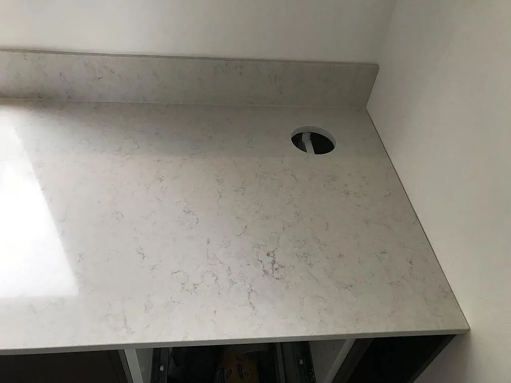 Köksbänkskiva i Silestone Snowy Ibiza med kranhål och uppvikt stänkskydd, polerad vit kvartskomposit i ett kök i Växjö.